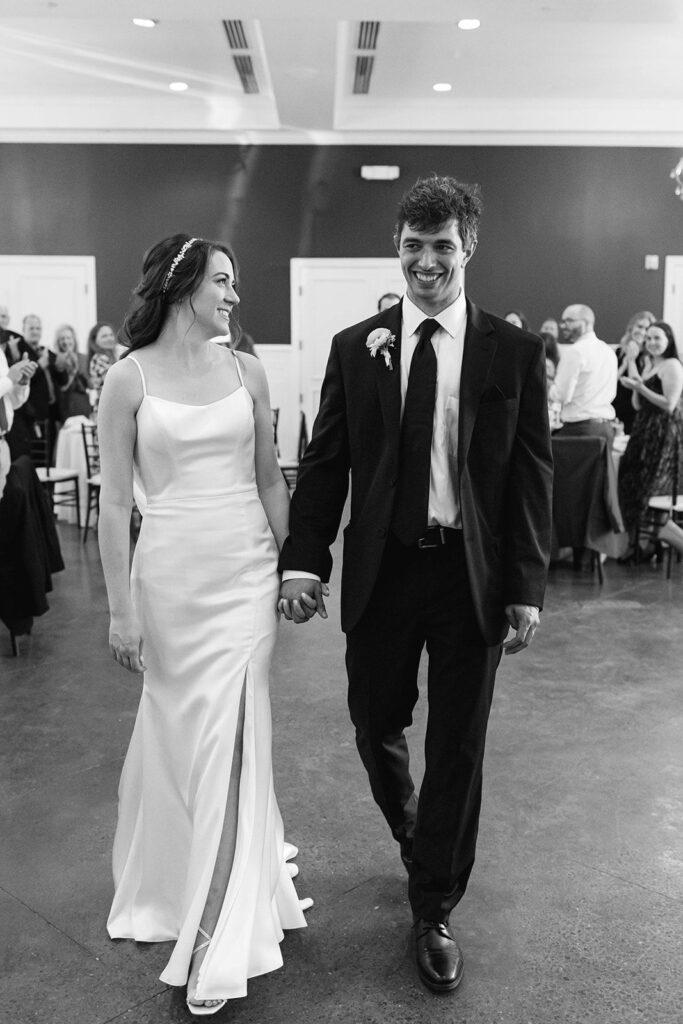 black and white image of bride and groom holding hands