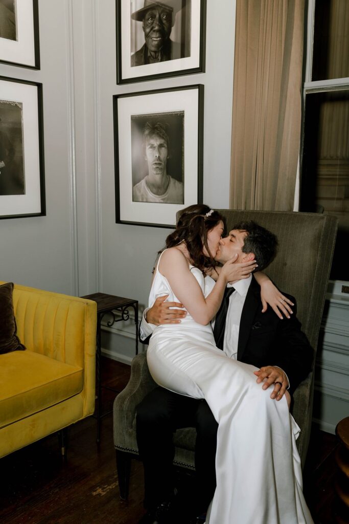 bride sitting on grooms lap giving him a kiss