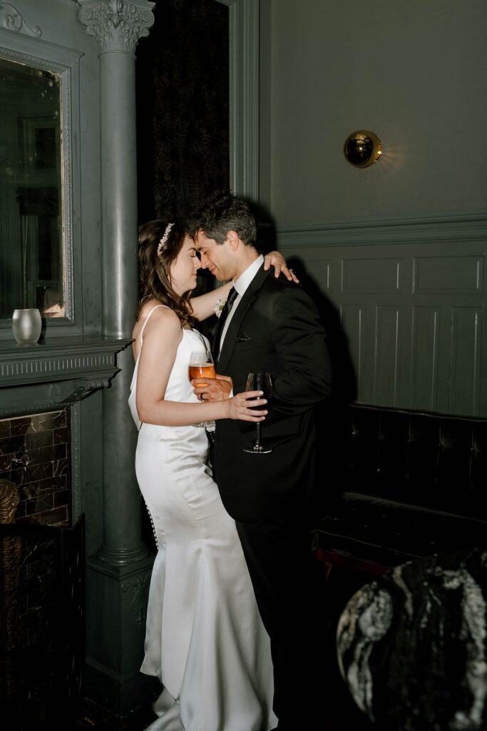 Bride and groom embrace while holding glasses of wine