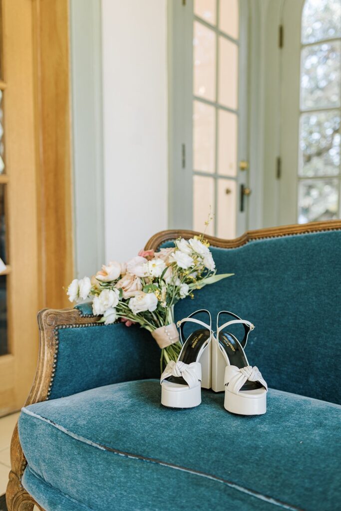 bridal wedding day shoes on blue velvet couch with bridal bouquet